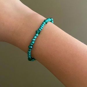 A teal bracelet with two different shades of teal beads